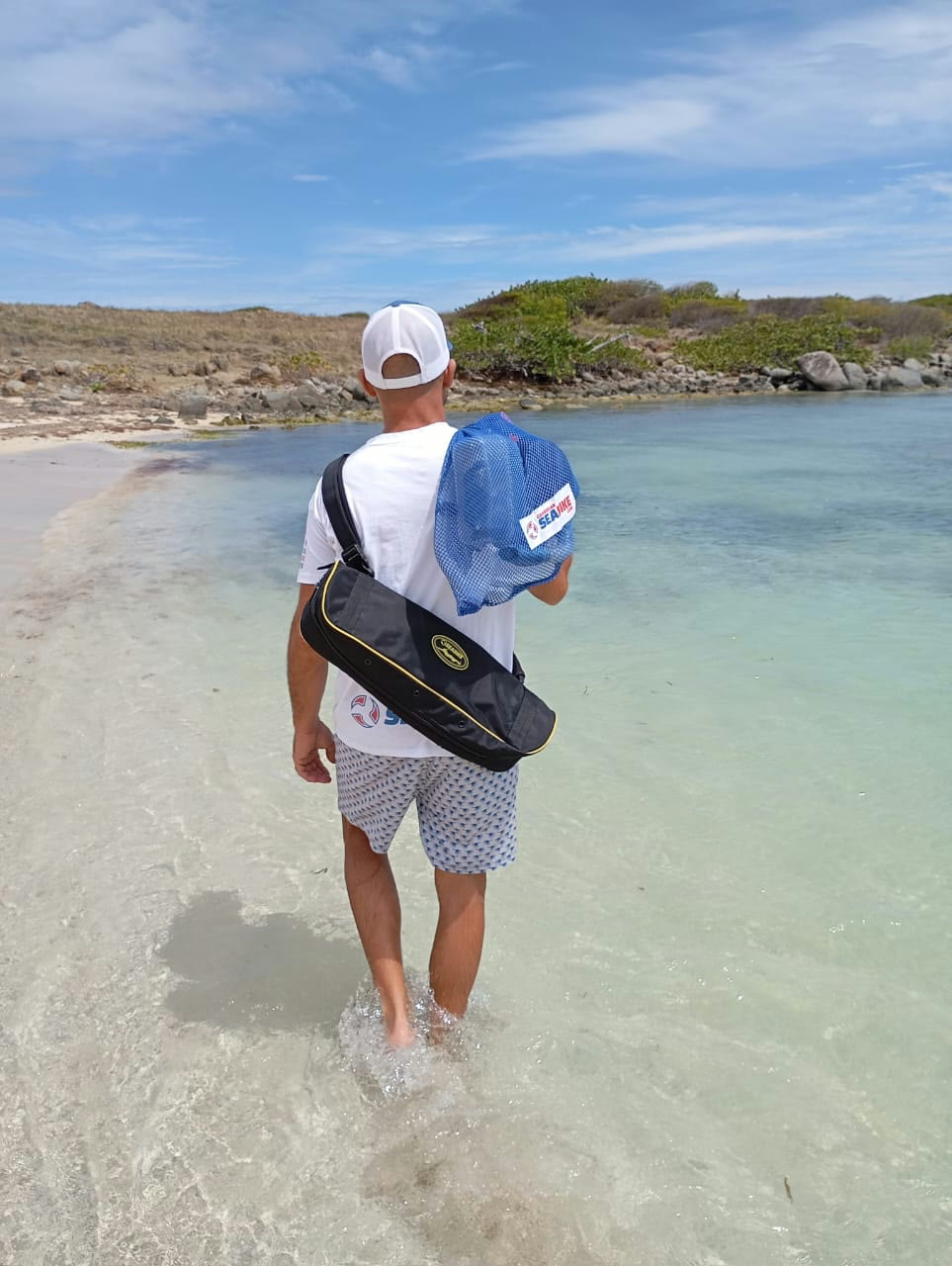 Guest walking a Maui Sea Board electric snorkeling board down the beach toward clear turquoise water